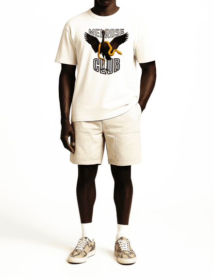 Melrose Club black swan graphic tee in off-white worn with beige shorts and patterned sneakers
